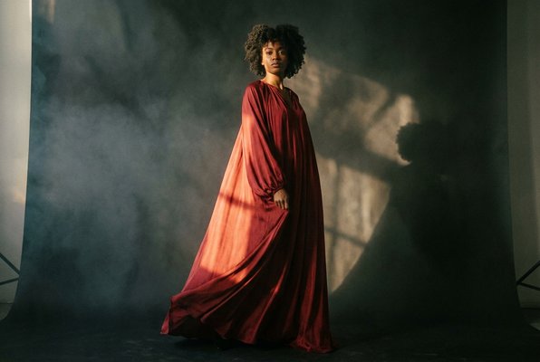 Amara Reign — full-length in flowing red gown, dramatic lighting